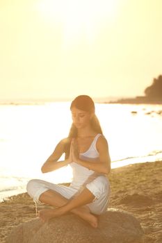 Young woman practicing yoga  near the ocean