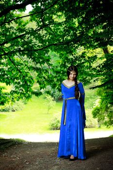 beautiful princess standing in shadow of big trees