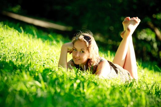 beautiful girl laying in grass on sunny meadow