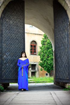 medieval girl on street of old town near big gates