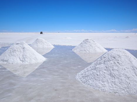 Piles of drying salt and reflection in the water at the Salar de Uyuni (salt flats) in Bolivia.