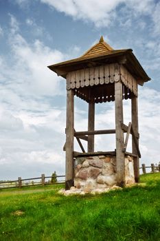 village well on green hill under cloudy sky