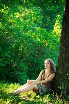 beautyful woman sitting next big tree