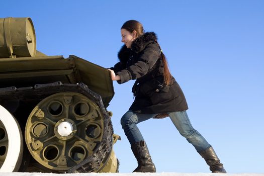 The girl pushes the tank monument on the background of blue sky