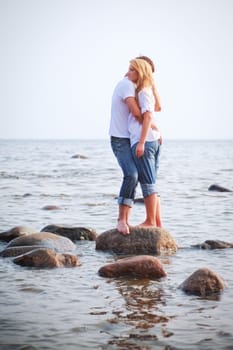 couple embrace on a big stone in sea