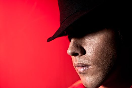 Handsome man portrait with hat dark eyes mistery and beauty concept on red background