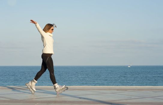 Acrobatic stance while skating along a sunny beach promenade