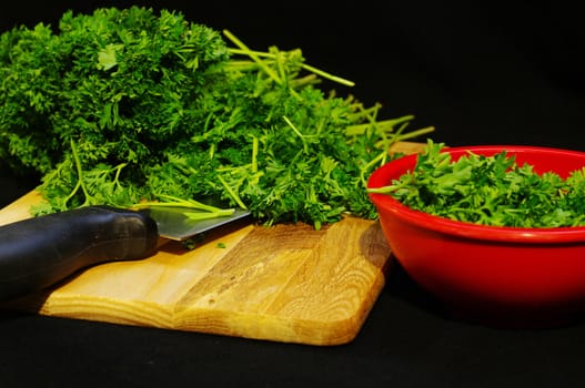Chopped parsley with a knife and a red bowl