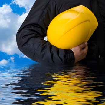 Closeup of Yellow helmet at builder hands on building background