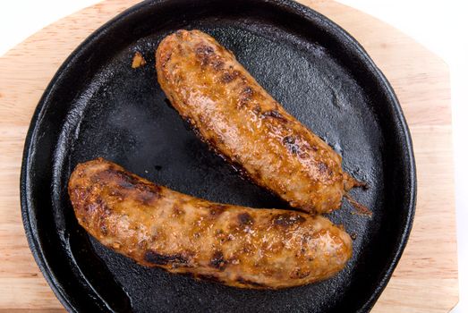 Roasted sausages close-up at pan on a white background