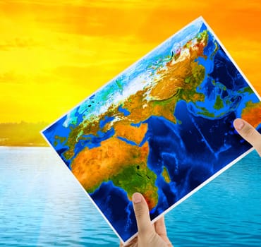Hand holding map at beauty sunset on Lake, and orange sky