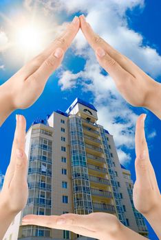 Hands showing home sign on blue modern building background