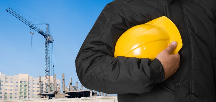 Closeup of builder with yellow helmet on building panorama background