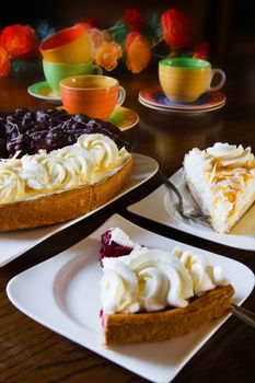 Different Dutch pastry or Limburgian flans with cups, mugs and flowers prepared for a party - vertical