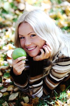 woman with green apple in autumn park