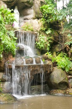 Waterfalls in the park. A statue of the goddess. Of Christianity.