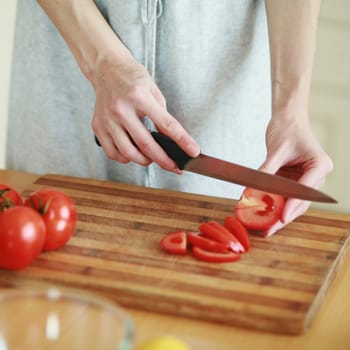 An image of hands cutting fresh tomatoes