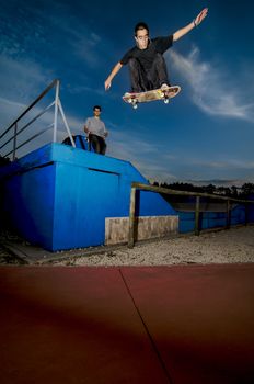 Skateboarder flying over a fap on sunset at the local skatepark.