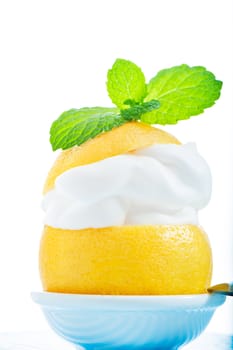 A fresh lemon with lemon cream and mint on the top on white background as a studio shot