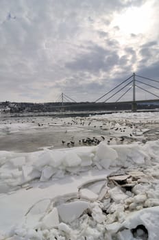 Danube river covered with ice and bridge behind