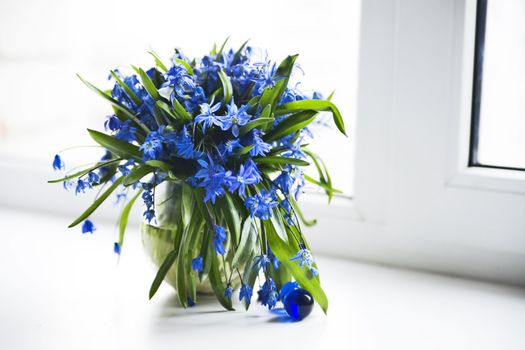 Fresh spring flowers in a vase on a window sill
