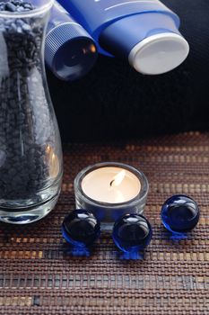 Creams for body care, candle and a blue pebble for spa treatment