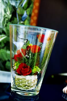 Small bouquet of roses in a glass as a romantic gift to wedding