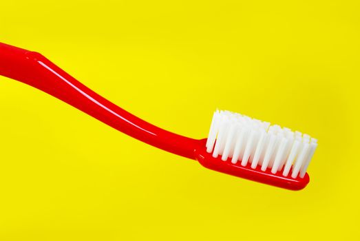 Red toothbrush on yellow background 