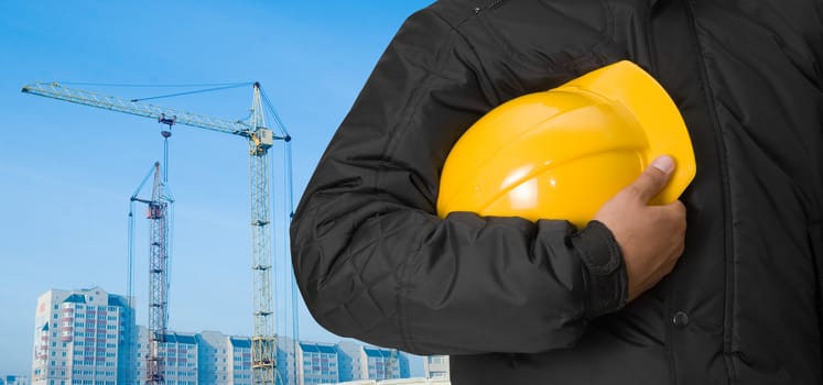 Closeup of builder with yellow helmet on building panorama background