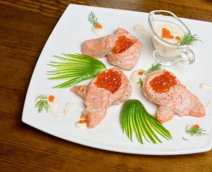 roasted salmon filet with red caviar, cucumbers and sauce