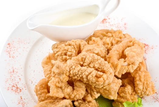Deep-fried squid with salad leaves, sauce, green and lemon on a white background