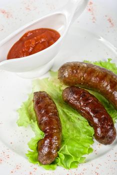 grilled venison sausage on a white with lettuce and sauce