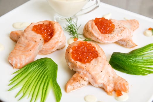 Fried salmon filet with red caviar, cucumbers and sauce