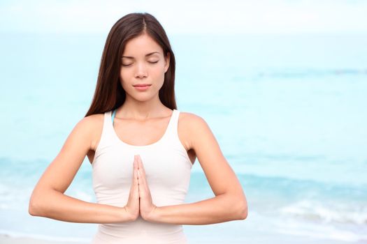 Yoga woman meditation. Young asian woman meditating doing yoga on beach. Beautiful serene mixed race Asian Chinese / Caucasian female fitness model relaxing on beach.