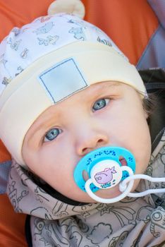 Toddler boy in cap with pacifier portrait