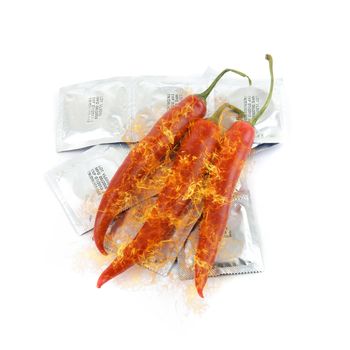 Red peppers on a condom packs at fire over white background