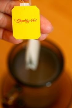Part of womans hand holding yellow label of tea