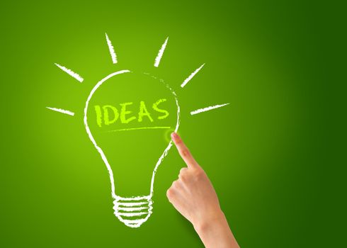 A Hand pointing of a Ideas Lightbulb on green background. 