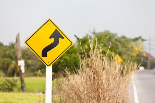 winding road sign in yellow and black on a country road ,Thailand