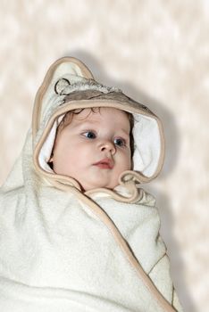 Beautiful baby wrapped in a brown blanket after bath