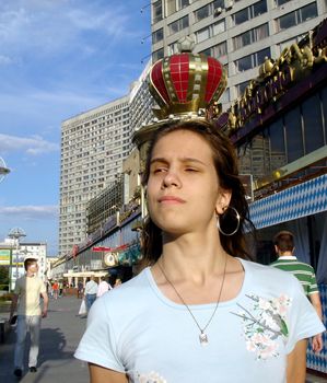 The proud girl like a queen moving by New Arbat street with a crown on a background under her head, Moscow, Russia