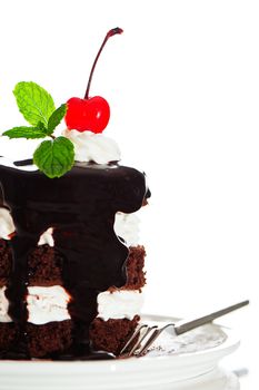 A small chocolate cake with 2 layer white cream, cherry and mint  on top on a white background as a studio shot