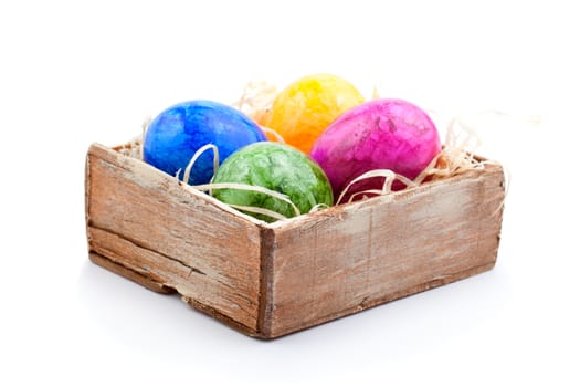 colored Easter eggs in the old box with straw