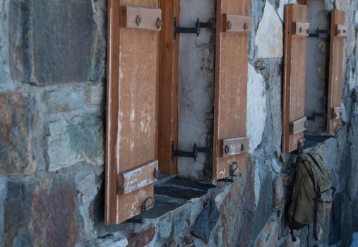 An old stone house in the Austrian alps with backpack hanging from a window slide