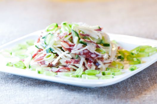 Cabbage salad, sausage, cucumber and green peas close up