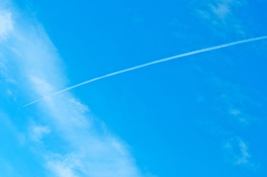 Trace of an airoplane on a cloudy blue sky