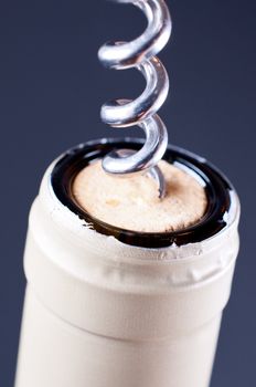 Corkscrew in cork in wine bottle on grey background close up