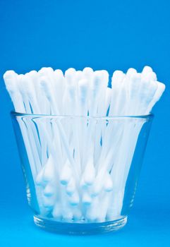 Cotton buds in glass on blue background