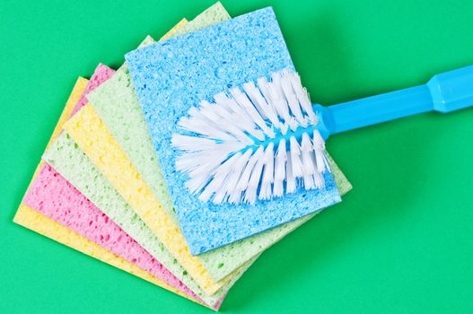 Brush and multi color sponges for cleaning on green background