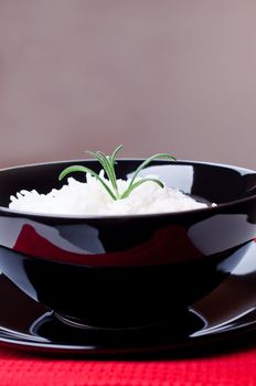 White rice in black round bowl on red tablecloth